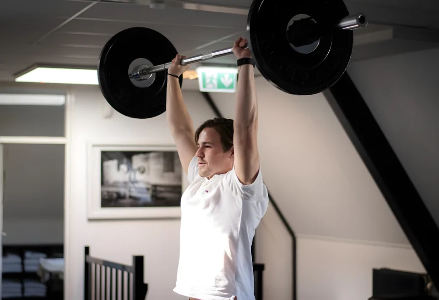 Trainer met een halter boven het hoofd